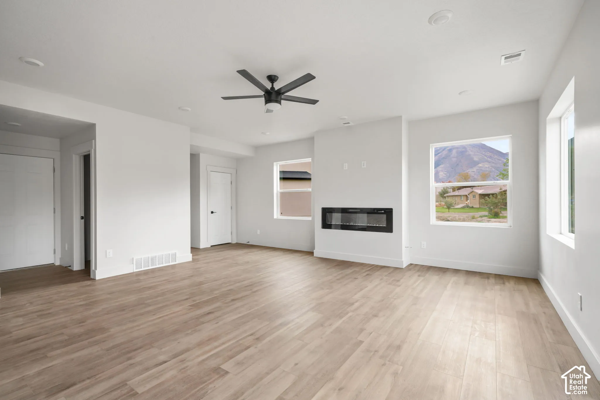 Living space featuring wood-finish flooring, a wall-mounted electric fireplace, recessed lighting, and a ceiling fan with mountain scenery