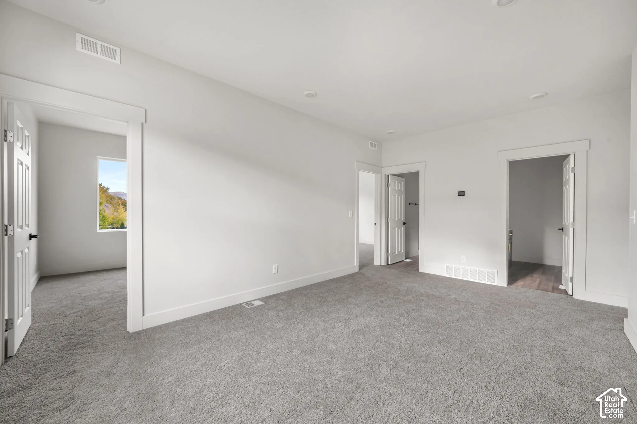Neutral-toned carpeting, recessed ceiling lighting, and solid-core interior doors with crisp trim molding