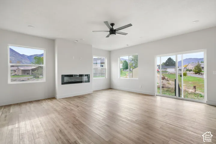 Living area featuring wood-finish flooring, a wall-mounted electric fireplace, recessed lighting, a modern ceiling fan, and sliding glass doors