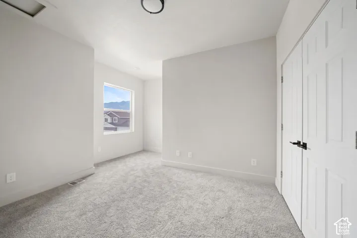 Neutral-toned interior featuring wall-to-wall carpeting, dual-panel closet doors with matte black hardware, and a single-hung window with mountain scenery