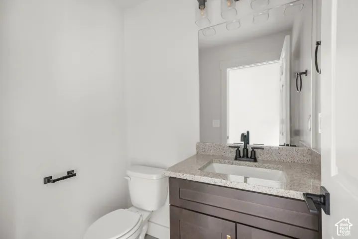 Dark wood-finish vanity with a stone-composite countertop, undermount rectangular basin, matte black faucet, and matching multi-light fixture above a large mirror