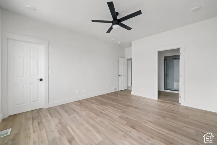 Room featuring wood-finish flooring, a matte black ceiling fan, six-panel interior doors with matte black hardware, and recessed lighting