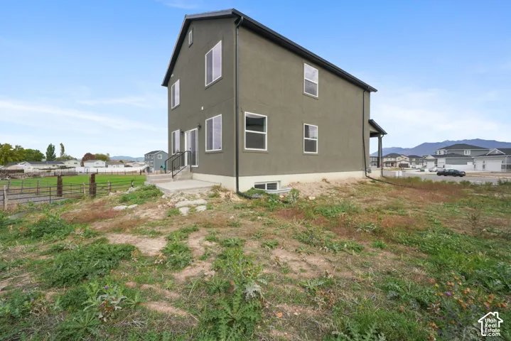 Two-story residence featuring stucco exterior, gabled roof, concrete rear patio, and metal railed stairs