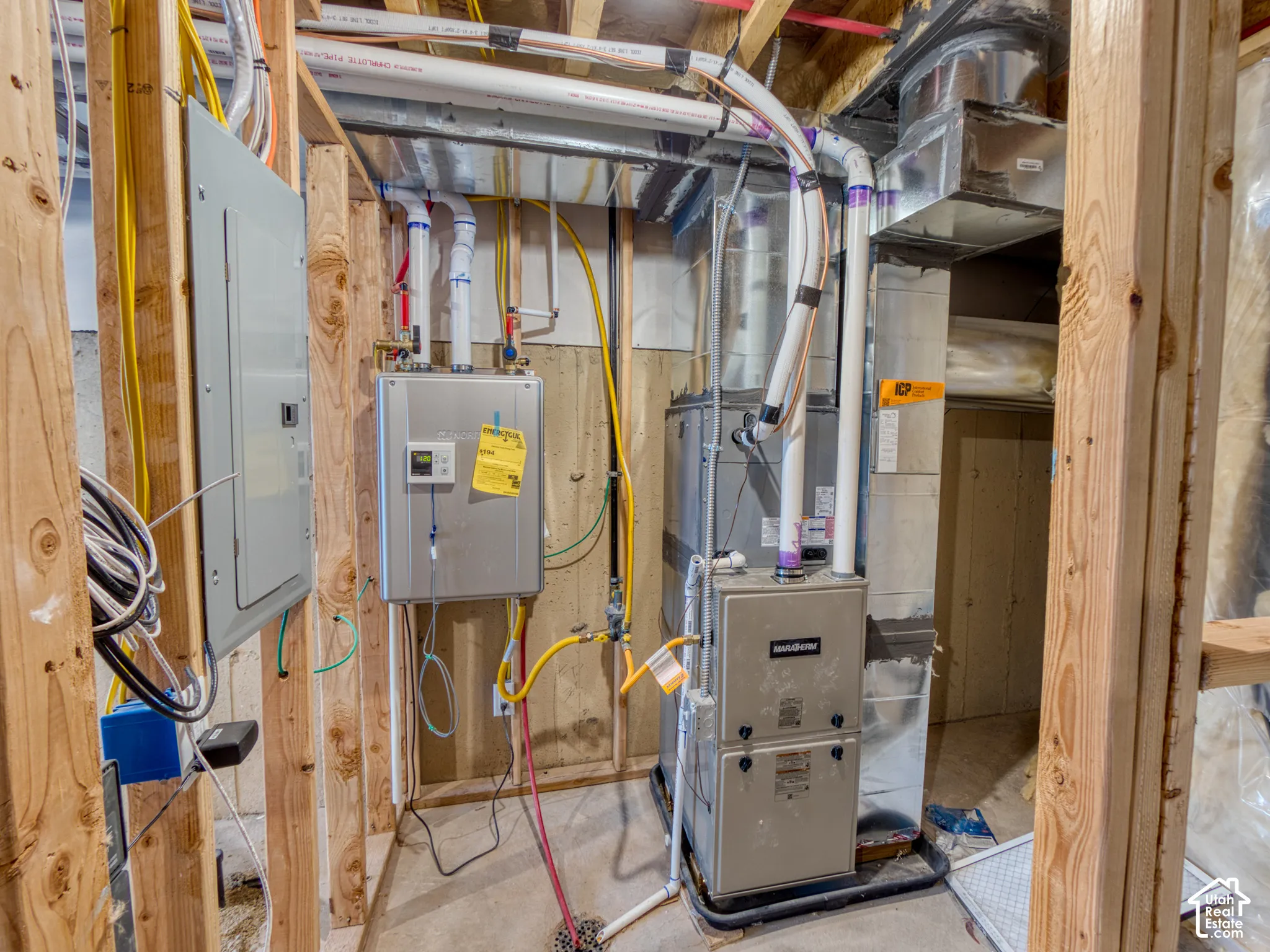 Mechanical area featuring a high-efficiency furnace, tankless water heater, electrical service panel, and exposed timber wall framing