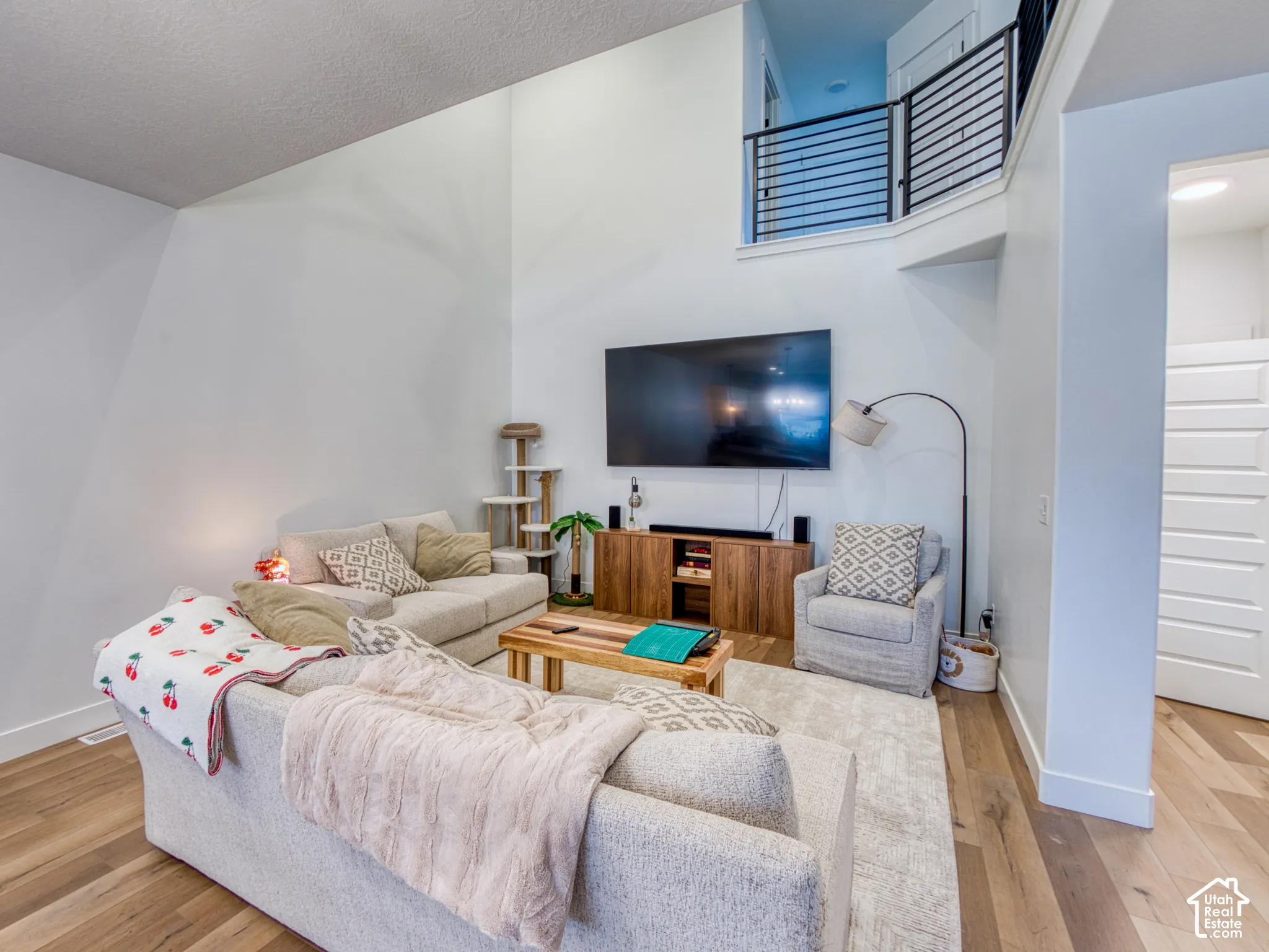 Double-height ceiling, wood-finish flooring, and black metal horizontal-slat mezzanine railing