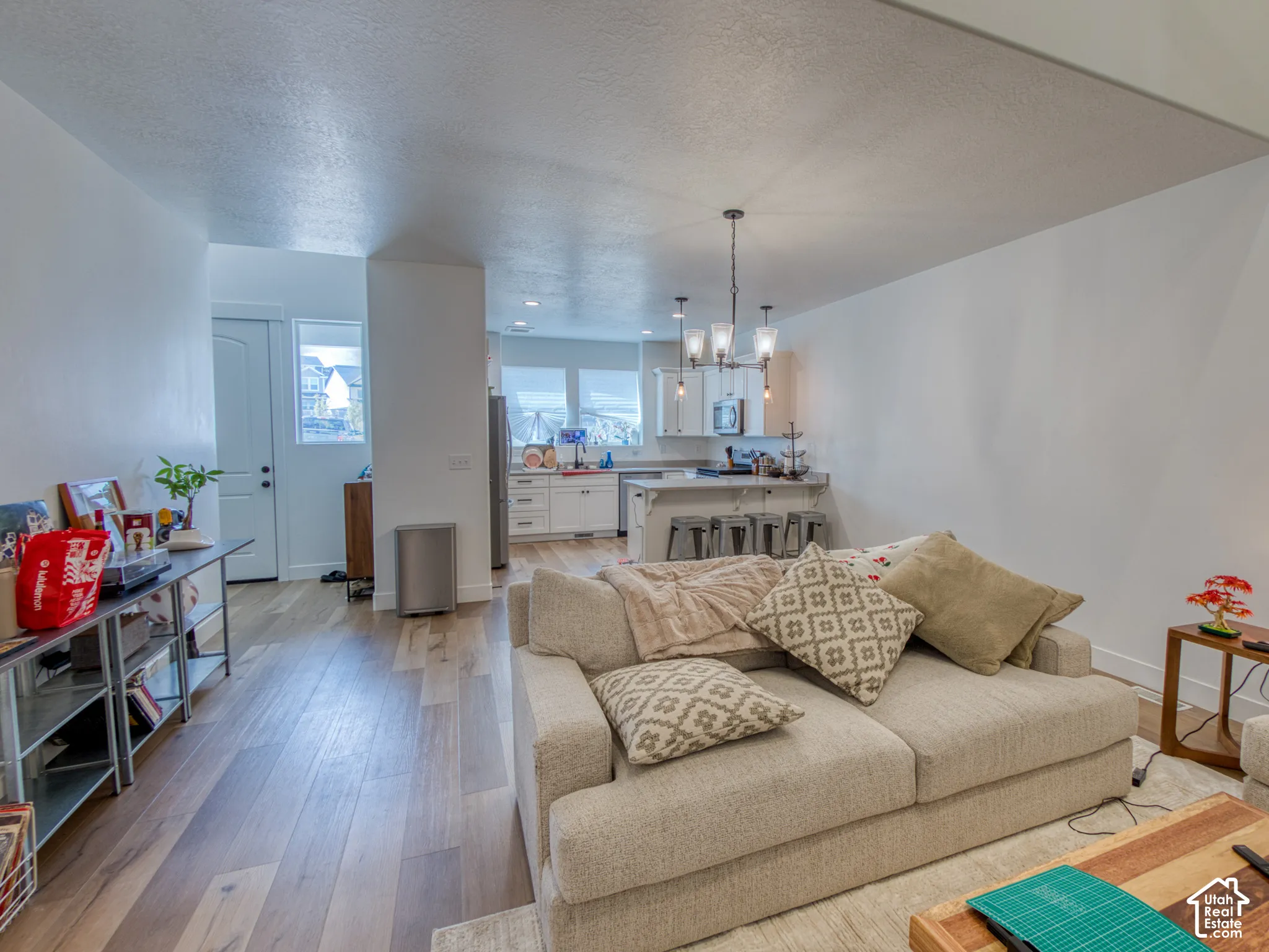 Open interior featuring wood-finish flooring, white cabinetry, multi-light chandelier, and center island
