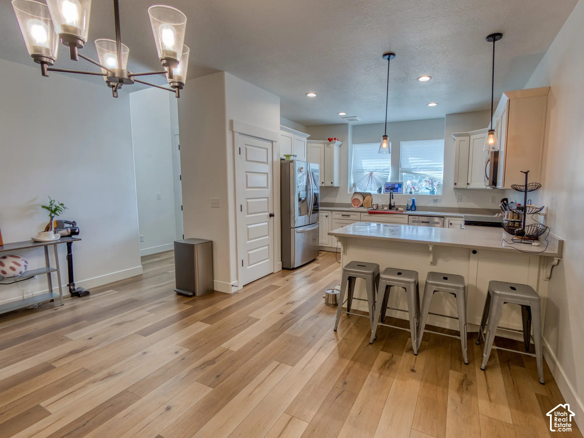 Kitchen featuring white cabinetry, wood-finish flooring, a quartz-topped breakfast bar, recessed lighting, and a multi-arm chandelier