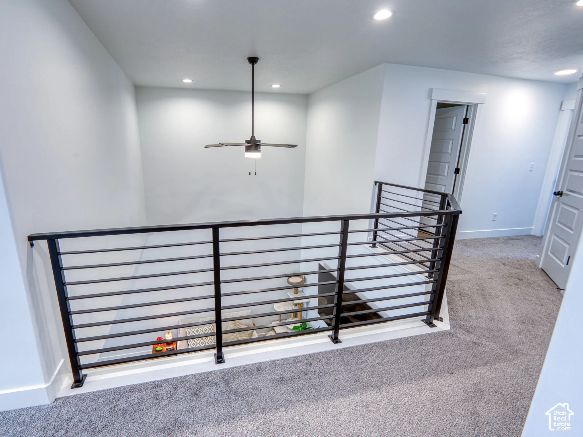 Metal horizontal-rail balustrade with integrated lighting, neutral wall-to-wall carpeting, and recessed ceiling lighting