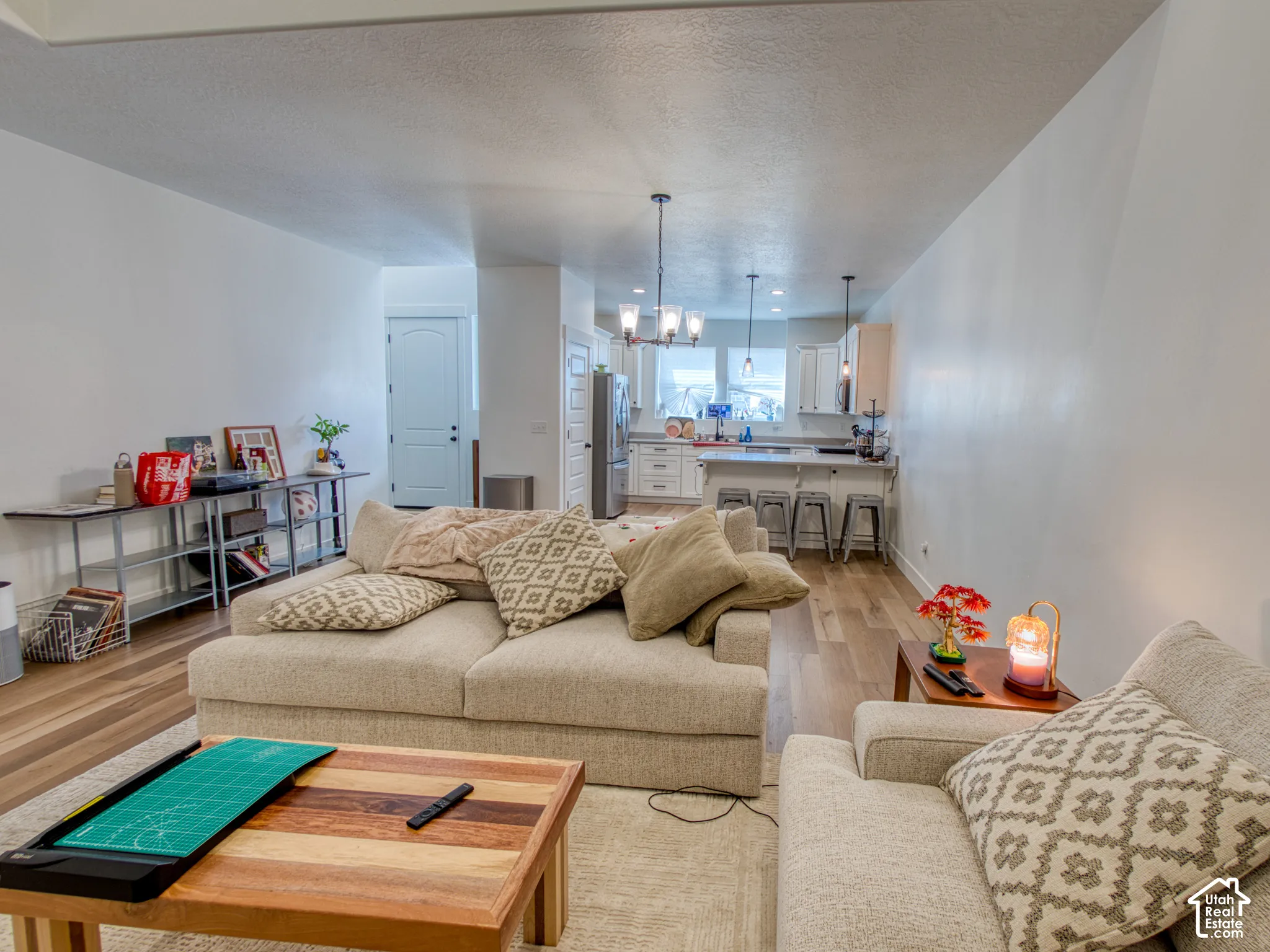Open-concept interior featuring wood-finish flooring, white cabinetry, a kitchen island with stone-surface countertop, and multi-light chandelier fixtures