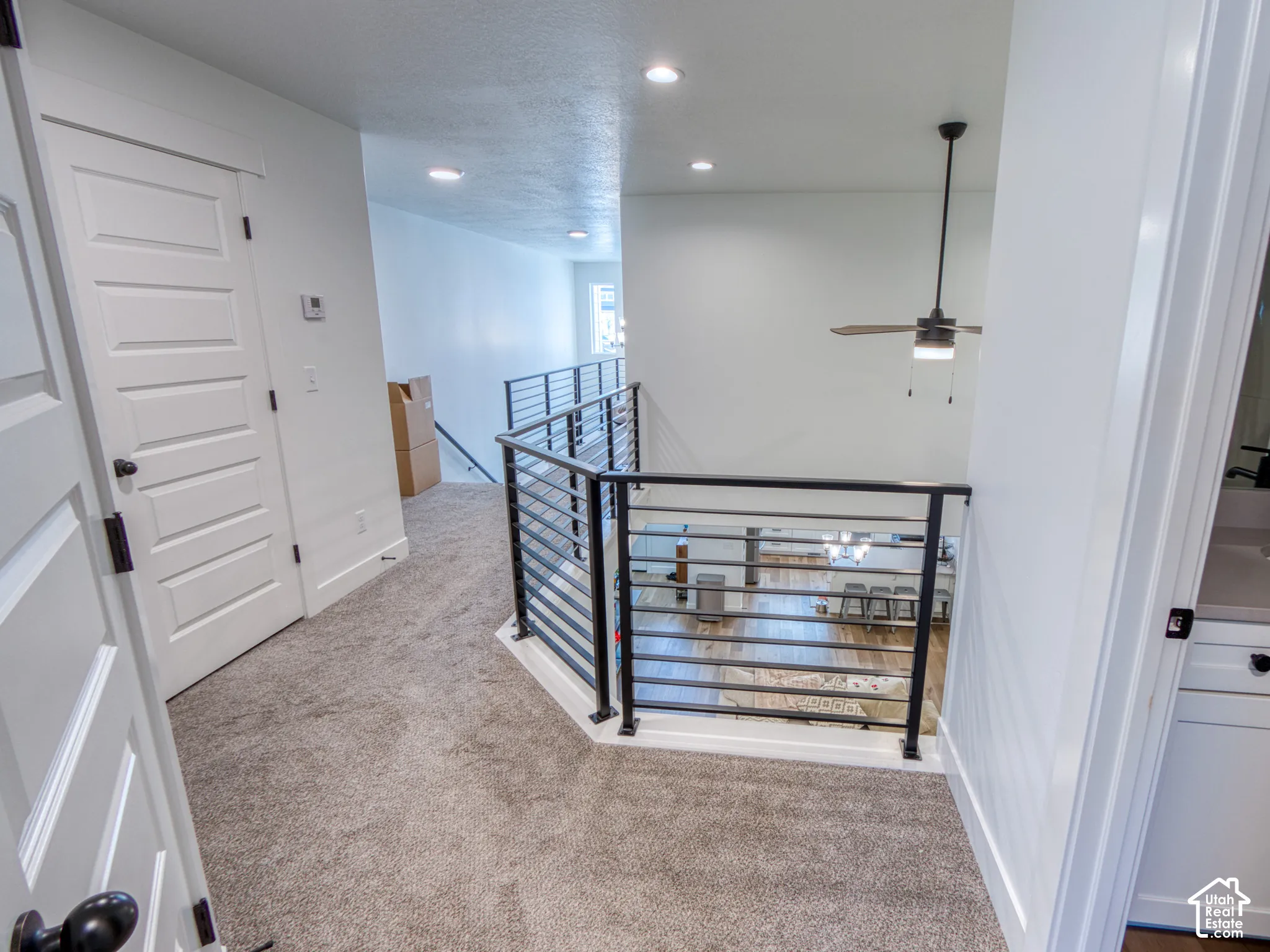 Metal horizontal railing, carpeted flooring, recessed ceiling lighting, and a modern ceiling fan