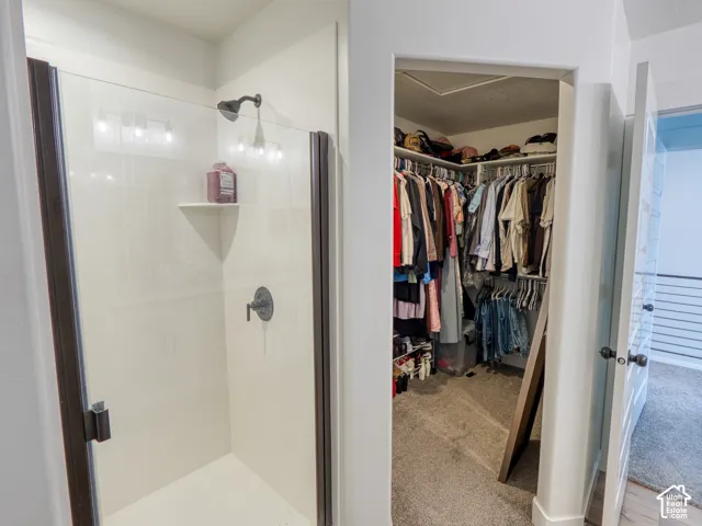 Master bathroom, Walk-in closet with integrated shelving and shower stall featuring a glass door, dark-finish metal frame, and wall-mounted shower fixture