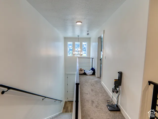 Hallway featuring a multi-light chandelier, horizontal metal stair railing, and tall windows