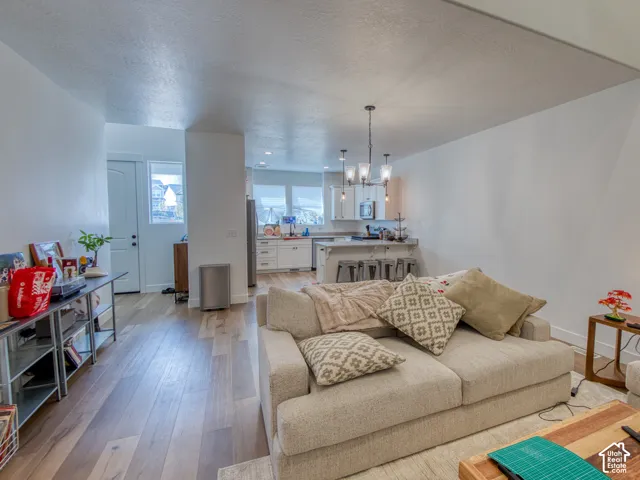 Open interior featuring wood-finish flooring, white cabinetry, multi-light chandelier, and center island