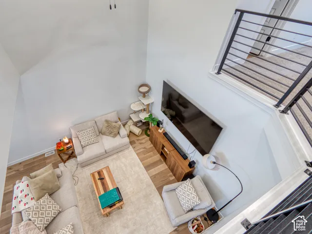 Double-height living area featuring wood-finish flooring and a metal horizontal-bar stair railing