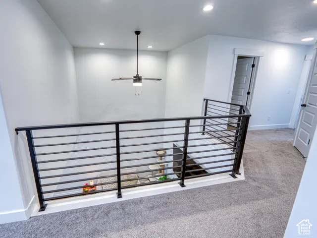 Metal horizontal-rail balustrade with integrated lighting, neutral wall-to-wall carpeting, and recessed ceiling lighting