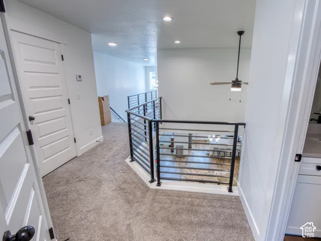 Metal horizontal railing, carpeted flooring, recessed ceiling lighting, and a modern ceiling fan