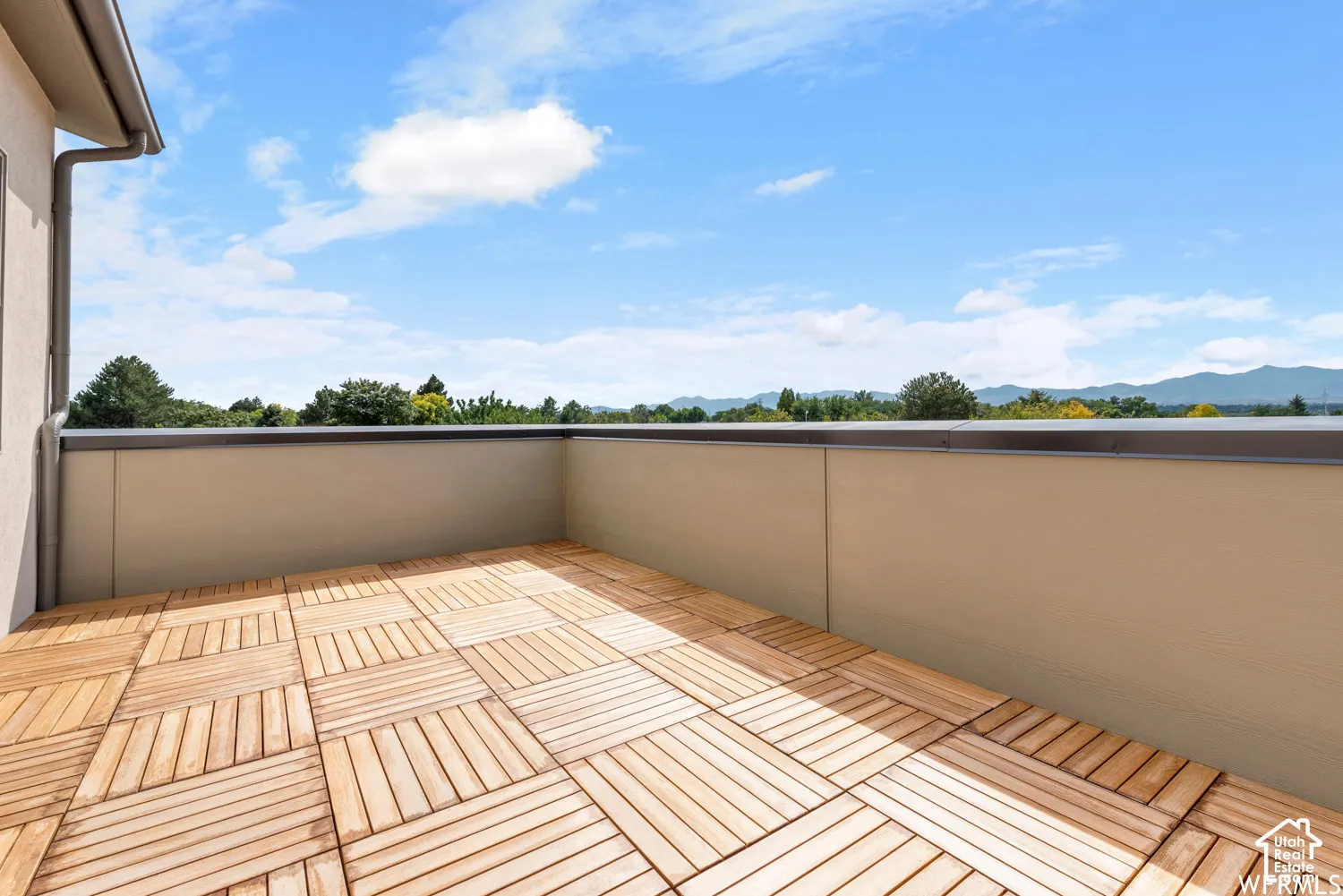 ORIGINAL PHOTOS Open-air terrace featuring modular wood-finish decking and solid perimeter wall enclosures with mountain backdrop