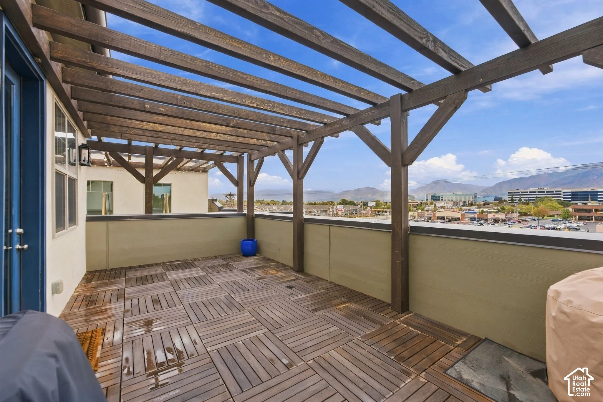 Rooftop deck featuring wood-finish decking, a stained wood pergola, and solid perimeter walls with metal capping