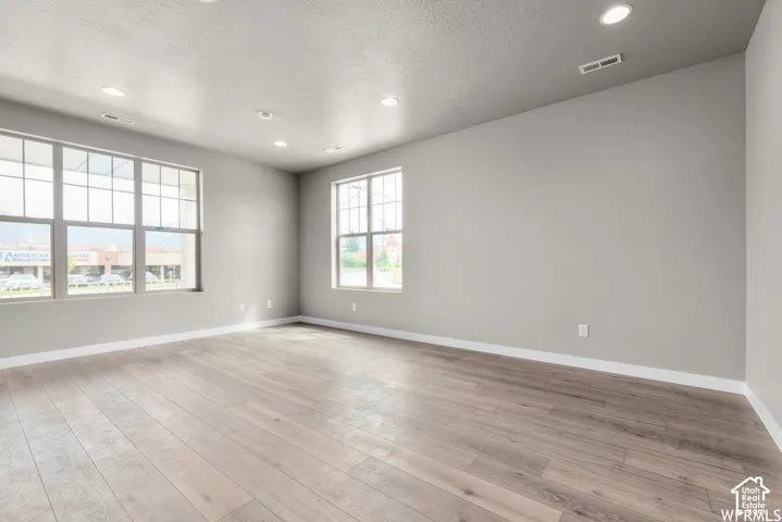 Neutral-toned interior featuring wood-finish flooring, recessed lighting, and expansive windows with grid detailing
