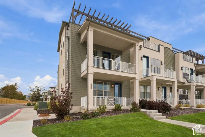 Multi-level exterior featuring shake-style siding, stone veneer accents, covered balconies with metal railings, and a structural roofline pergola