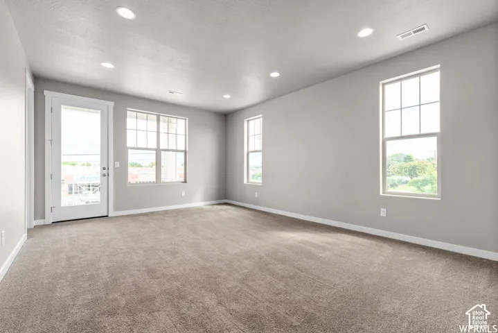 Neutral interior space featuring recessed lighting, wall-to-wall carpeting, multiple grid-pattern windows, and a glass-paneled exterior door