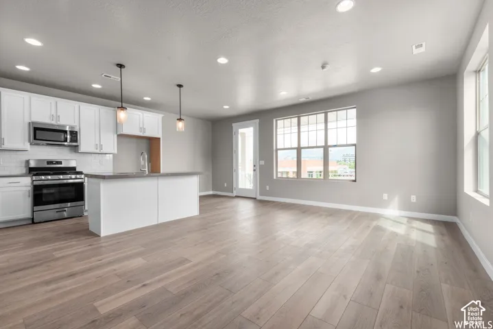 Kitchen featuring white cabinetry, wood-finish flooring, recessed lighting, pendant fixtures, and a center island