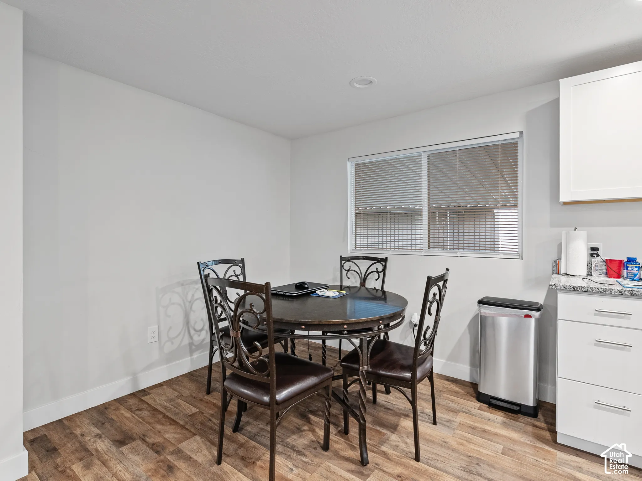 Wood-finish flooring, white shaker-style cabinetry, stone-finish countertops, and recessed lighting