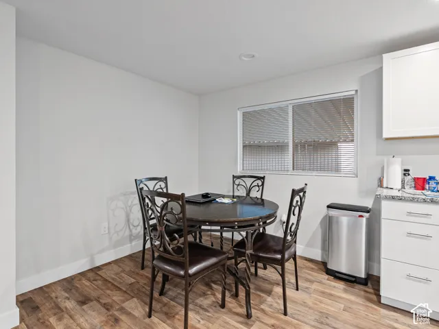 Wood-finish flooring, white shaker-style cabinetry, stone-finish countertops, and recessed lighting