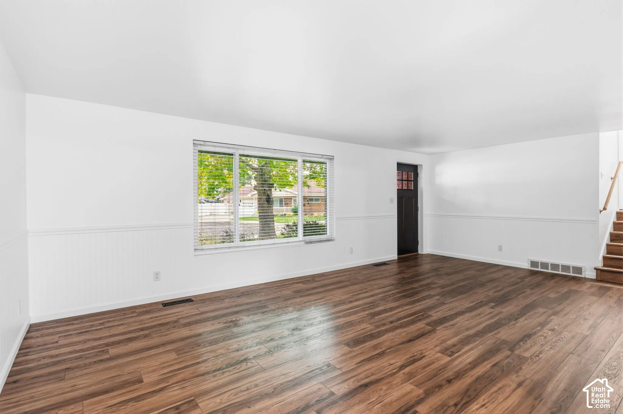 Interior space featuring wood-finish flooring, white beadboard wainscoting, and a large picture window
