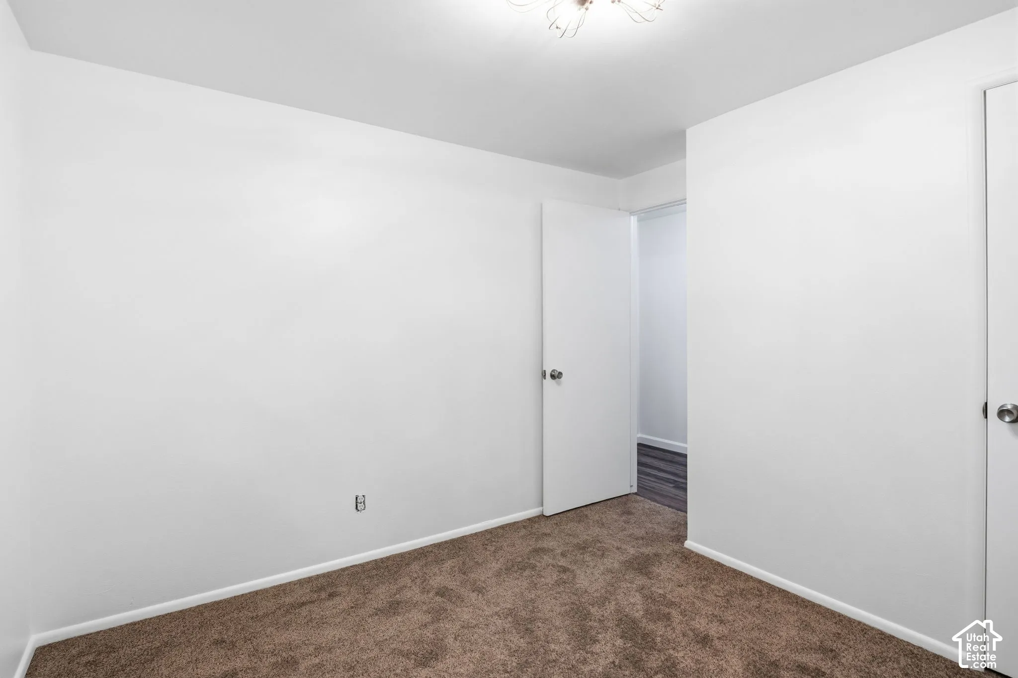 Interior space featuring neutral wall tones, wall-to-wall carpeting, and a multi-arm flush-mount light fixture