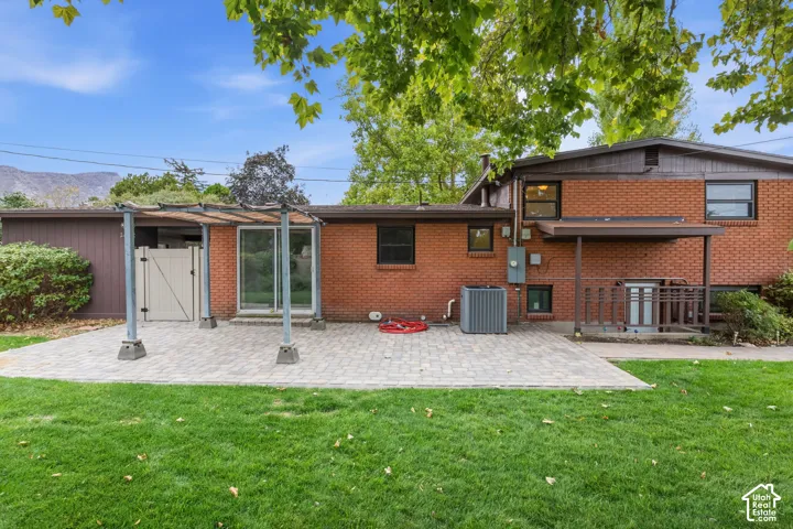 Brick exterior featuring a new paver stone patio, metal pergola, sliding glass door, and fenced backyard