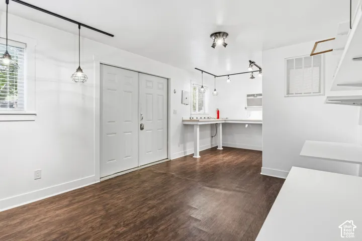Wood-finish flooring, double entry doors, industrial-style pendant lighting, track lighting, and built-in workstation surfaces