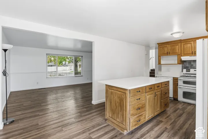 Kitchen featuring stained wood cabinetry, a central island with a white countertop, and wood-finish flooring throughout