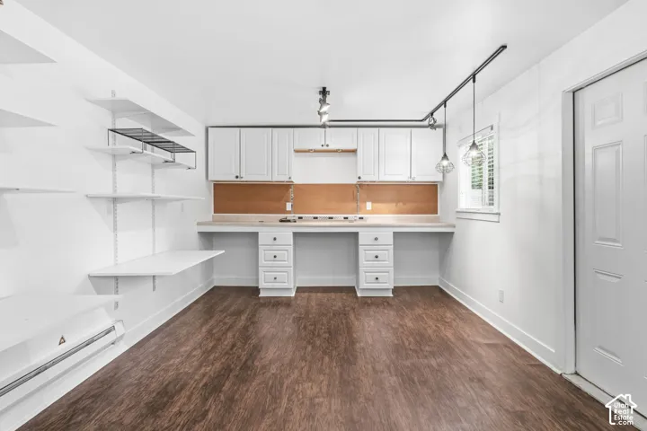 White cabinetry featuring built-in lower drawers, solid-surface countertops, wood-finish flooring, adjustable wall-mounted shelving, and industrial-style track lighting