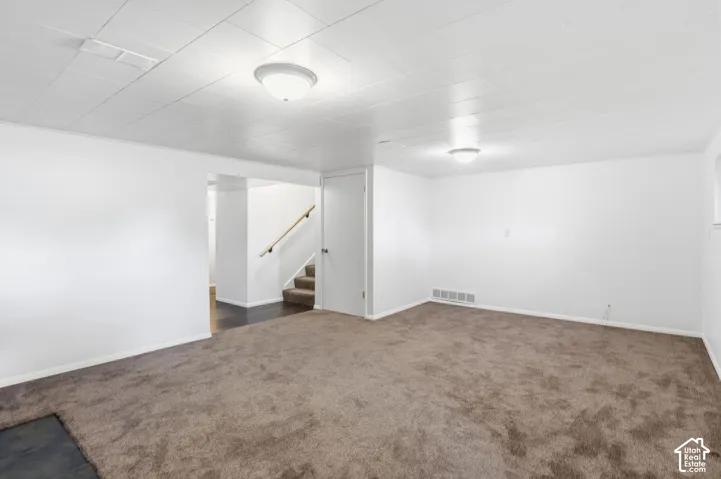 Stairs leading to level 1from basement 1 family room. Neutral-toned carpeted flooring, white panel ceiling, flush-mount lighting, and solid-core interior door