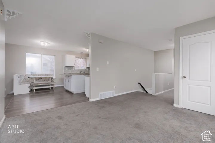 Open-concept area featuring neutral wall paint, wood-finish flooring, wall-to-wall carpeting, and decorative corbel accents