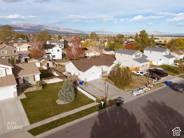 Single-story residence featuring an attached garage, concrete driveway, front yard lawn, and mountain backdrop