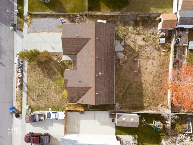 Aerial perspective featuring a multi-gabled roofline, concrete driveway, and detached storage structure situated on a large lot