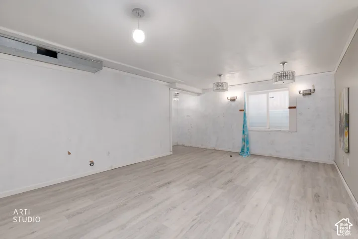 Open interior space featuring wood-finish flooring, recessed drum-style light fixtures, and wall-mounted sconces