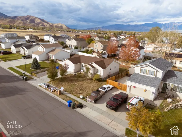 Aerial perspective of the residential property featuring a paved driveway, attached garage, and mountain backdrop
