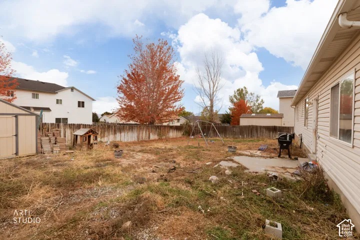 Backyard featuring horizontal wood fencing, a concrete patio, and a detached storage shed