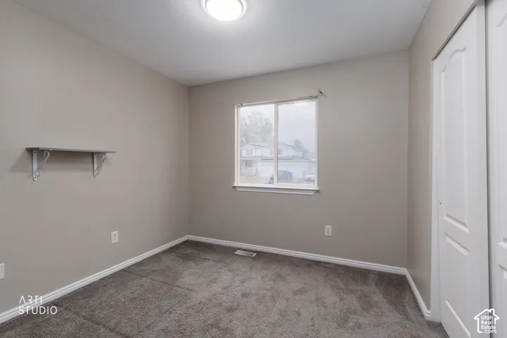Neutral-toned interior featuring wall-to-wall carpeting, a single window, and a built-in wall shelf