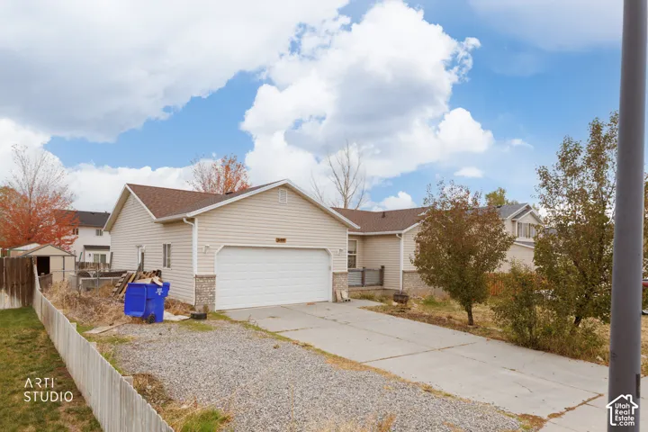 Exterior elevation featuring vinyl siding, stone-veneer accents, an attached two-car garage, and a concrete driveway