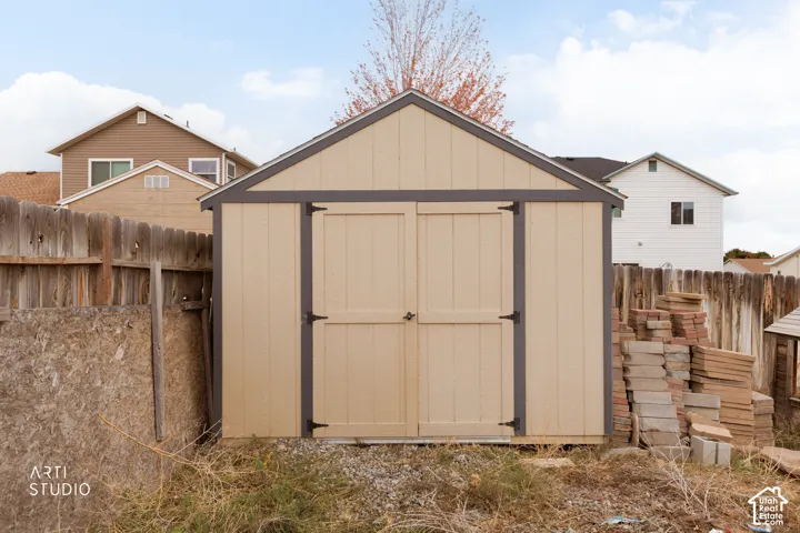 Storage shed featuring a gable roof, wood-panel siding, and double-door entry