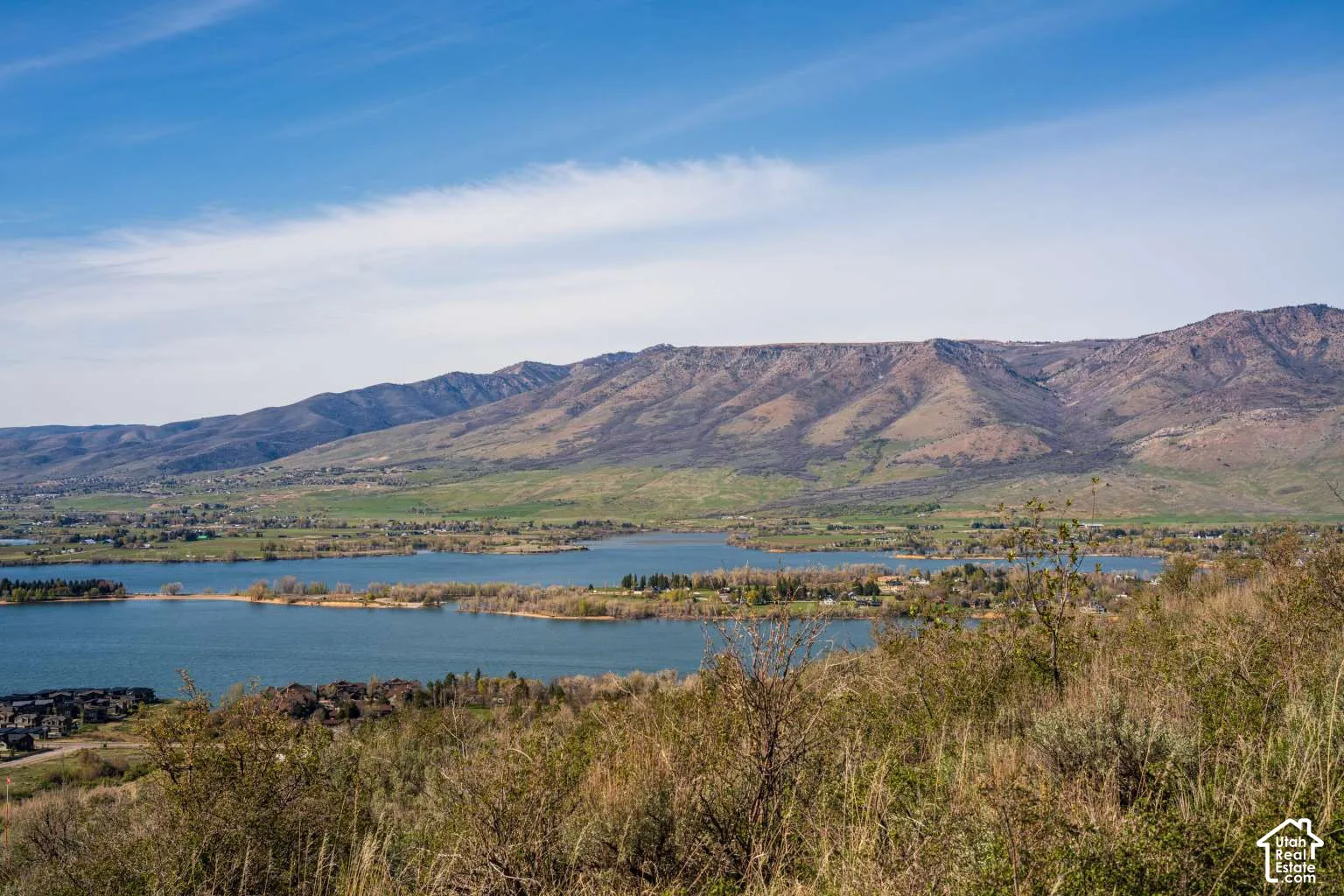 Expansive landscape featuring an open water reservoir, shoreline greenery, and prominent mountain ridgeline