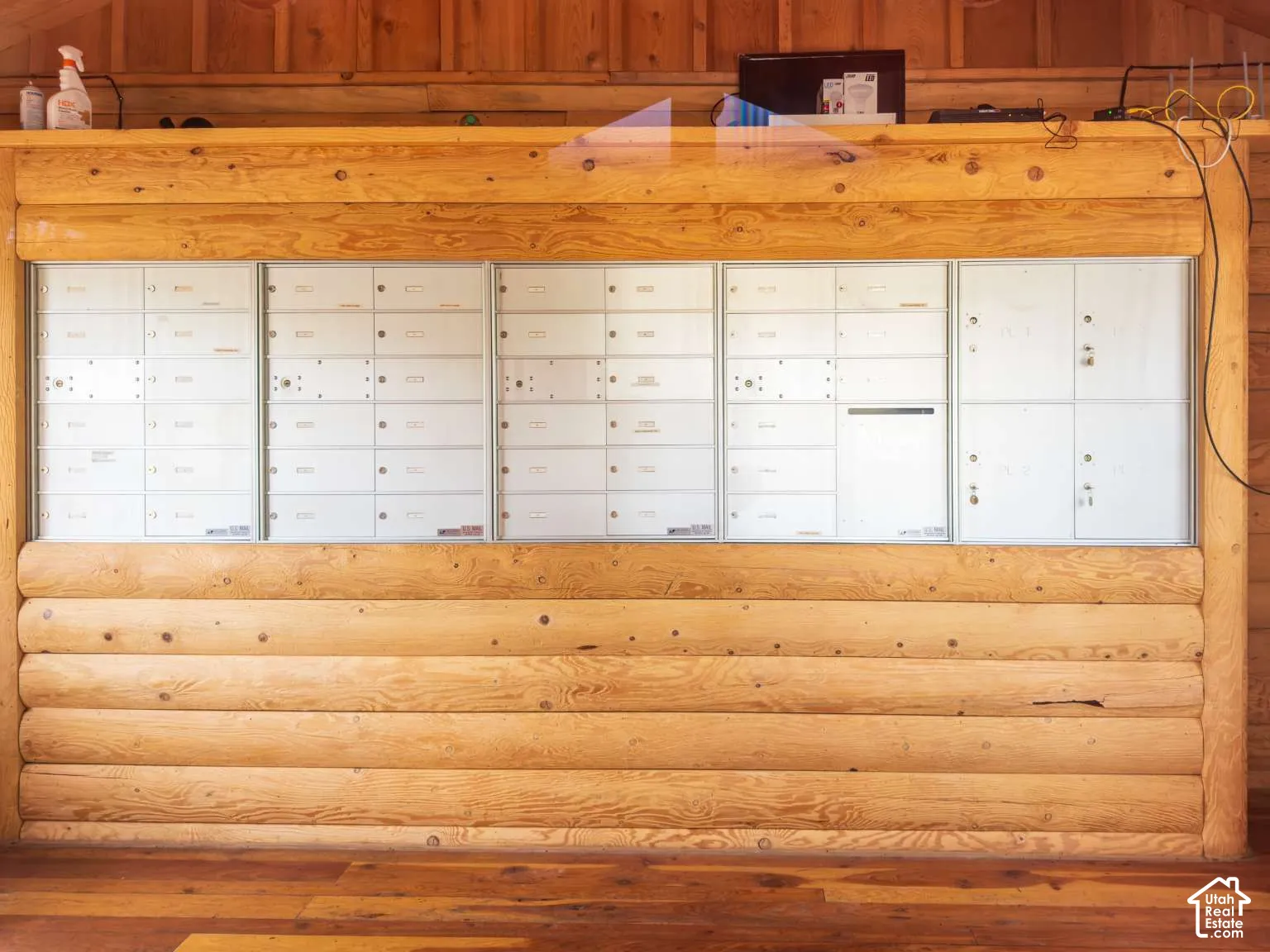 Integrated bank of mail lockers framed by exposed horizontal log walls and wood-finish flooring