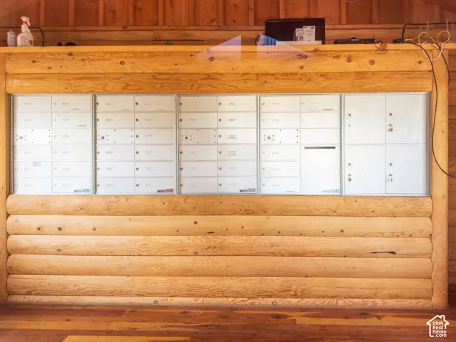 Integrated bank of mail lockers framed by exposed horizontal log walls and wood-finish flooring