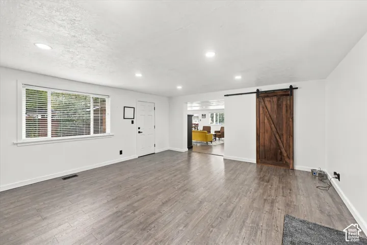 Interior space featuring wood-finish flooring, recessed lighting, and a dark-stained wood sliding barn door with black iron hardware