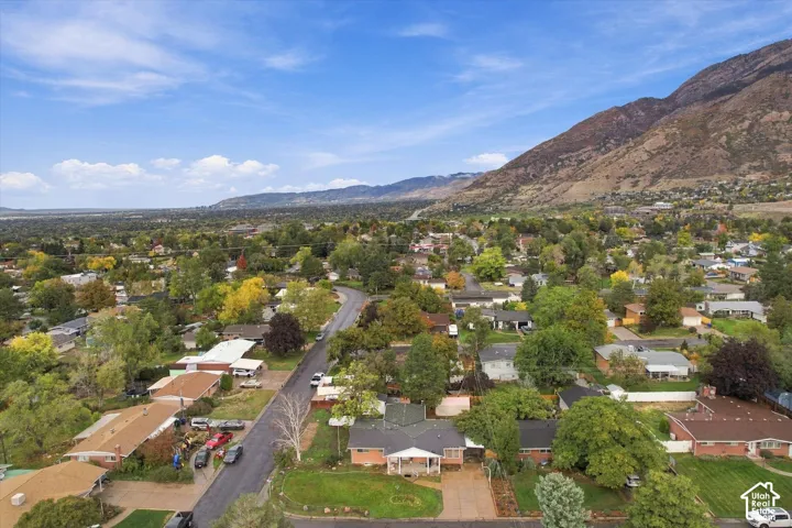 Aerial perspective showcasing an expansive residential lot with mature trees and a mountain backdrop