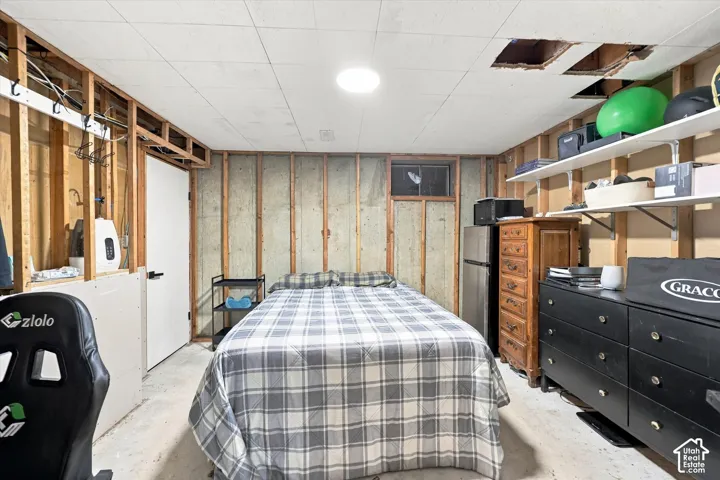 Unfinished room featuring exposed wood stud framing, concrete wall construction, ceiling-mounted light fixture, and an egress-style window
